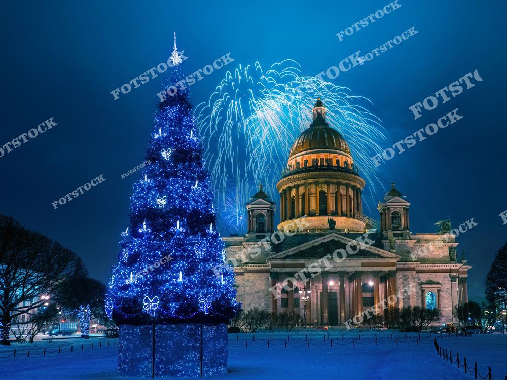На переднем плане расположена ярко украшенная рождественская елка, сияющая синей иллюминацией. На заднем плане виден величественный Исаакиевский собор, над которым в ночном небе сверкает праздничный фейерверк. Зимний Санкт-Петербург преображается в эту волшебную ночь, наполняя пространство атмосферой праздника. Красота архитектуры и праздничных декораций сливаются в гармонии.